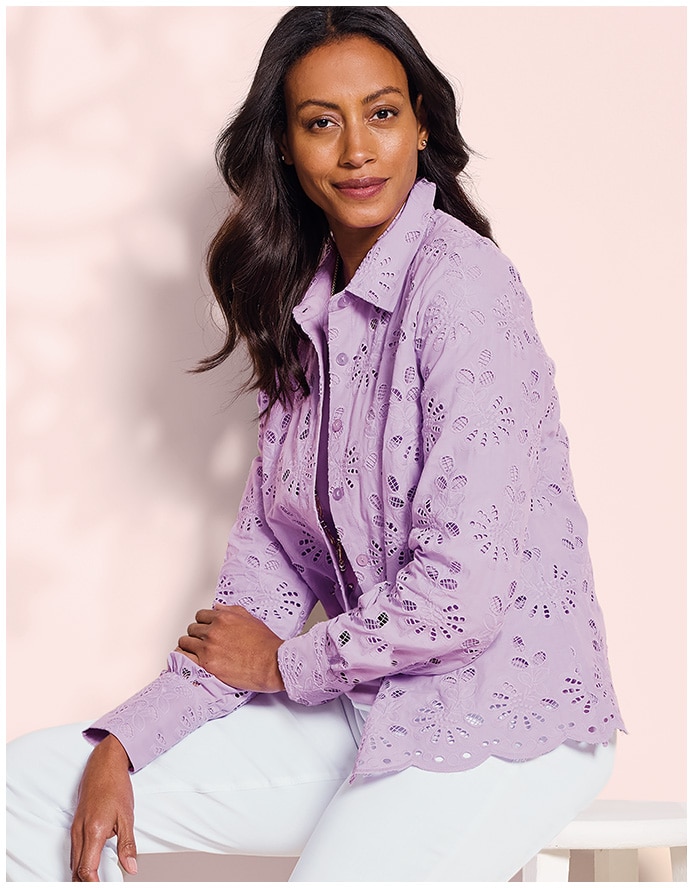 seated woman smiling into camera, wearing a pink jacket and white pants