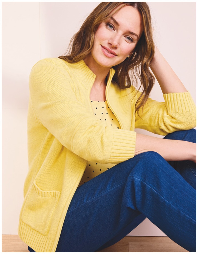 women sitting on a wooden floor, wearing a yelloe 3/4 sleeve cardigan, yellow shirt and blue jeans