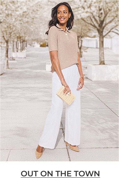 Woman looking to the right, wearing a tan linen-like short-sleeve blouse and white pants, holding a small purse